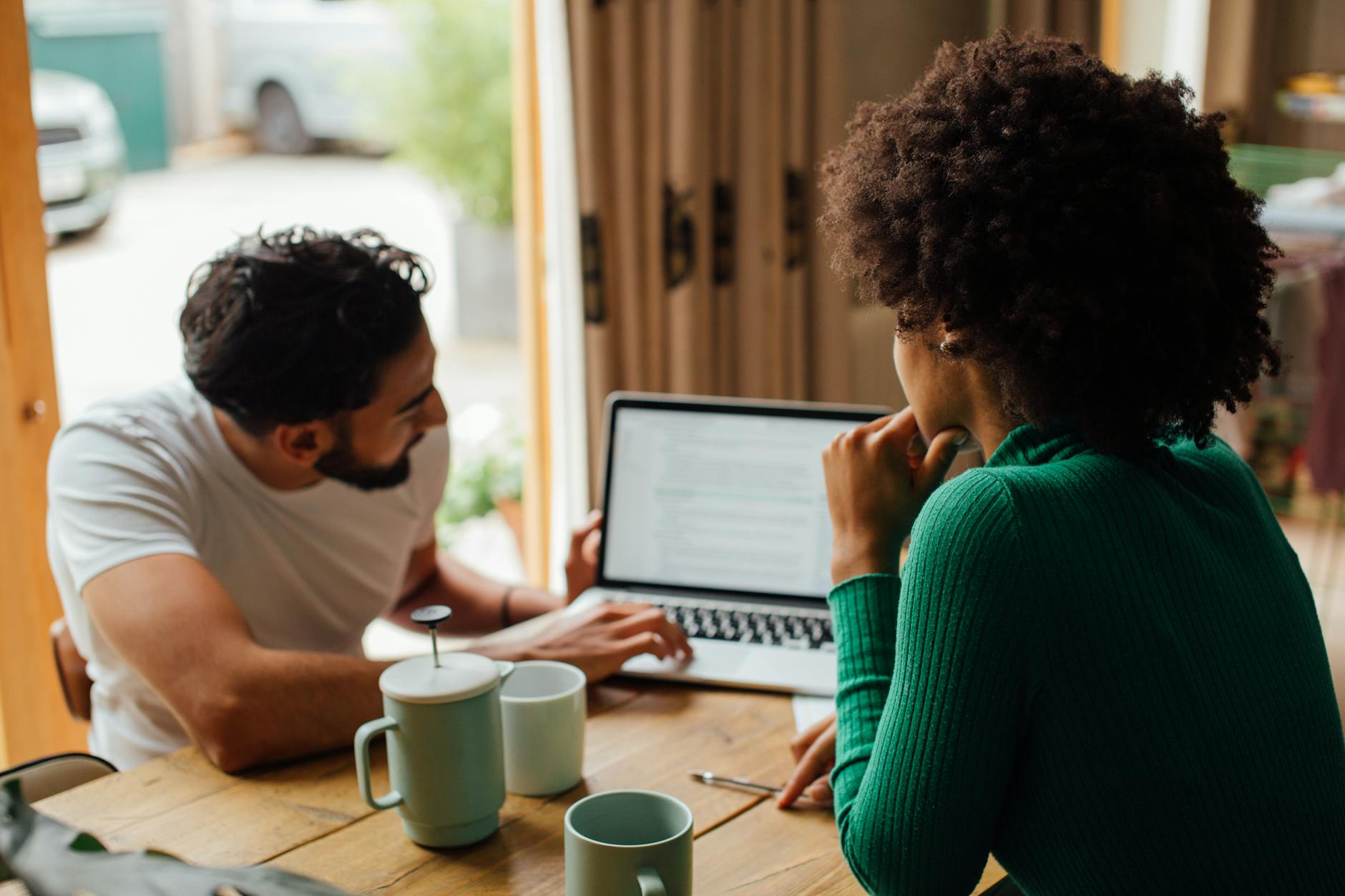 man and woman sitting at table using macbook